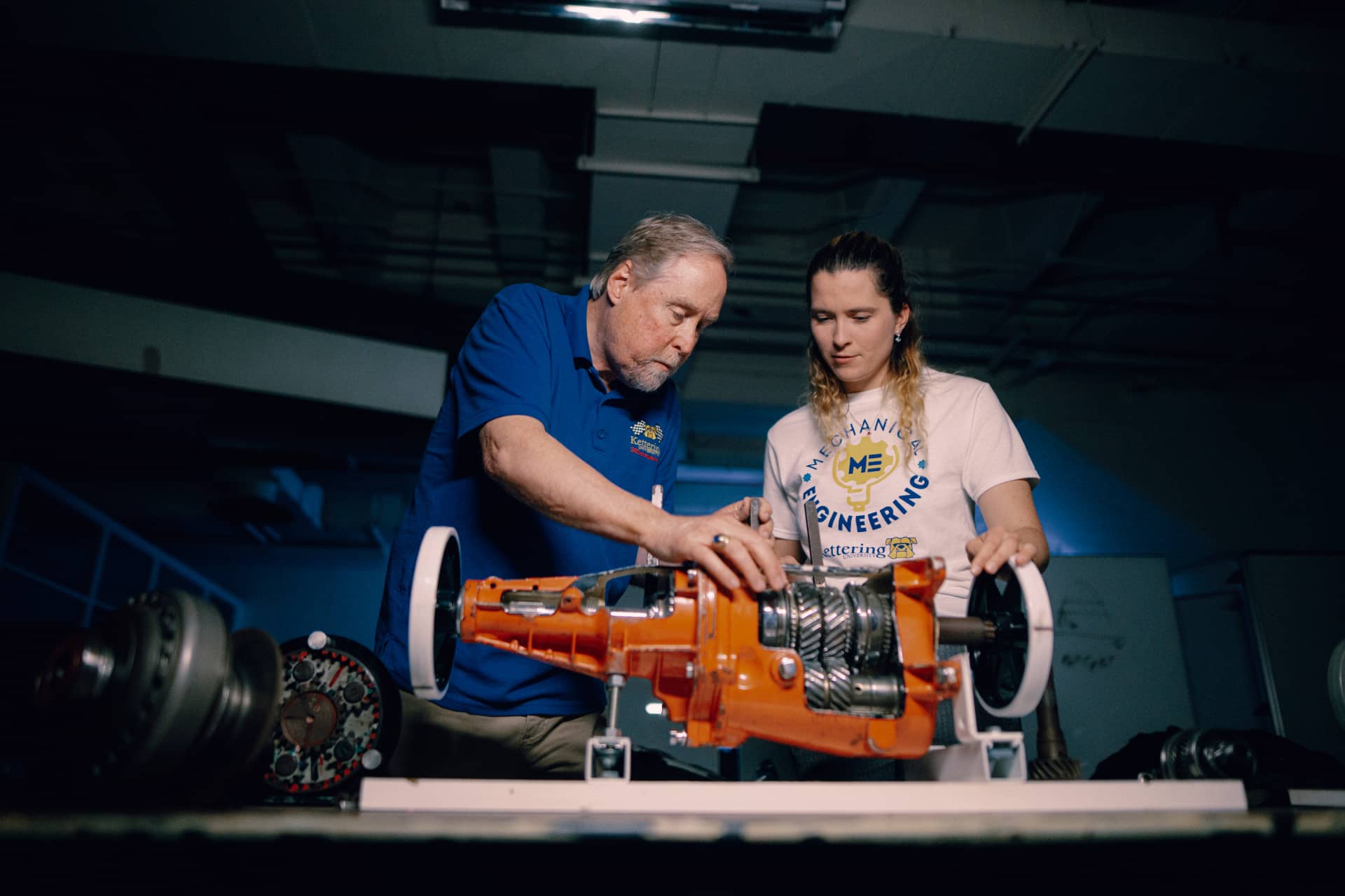 A Kettering professor and mechanical engineering student look at a transmission on display at the Car Lab