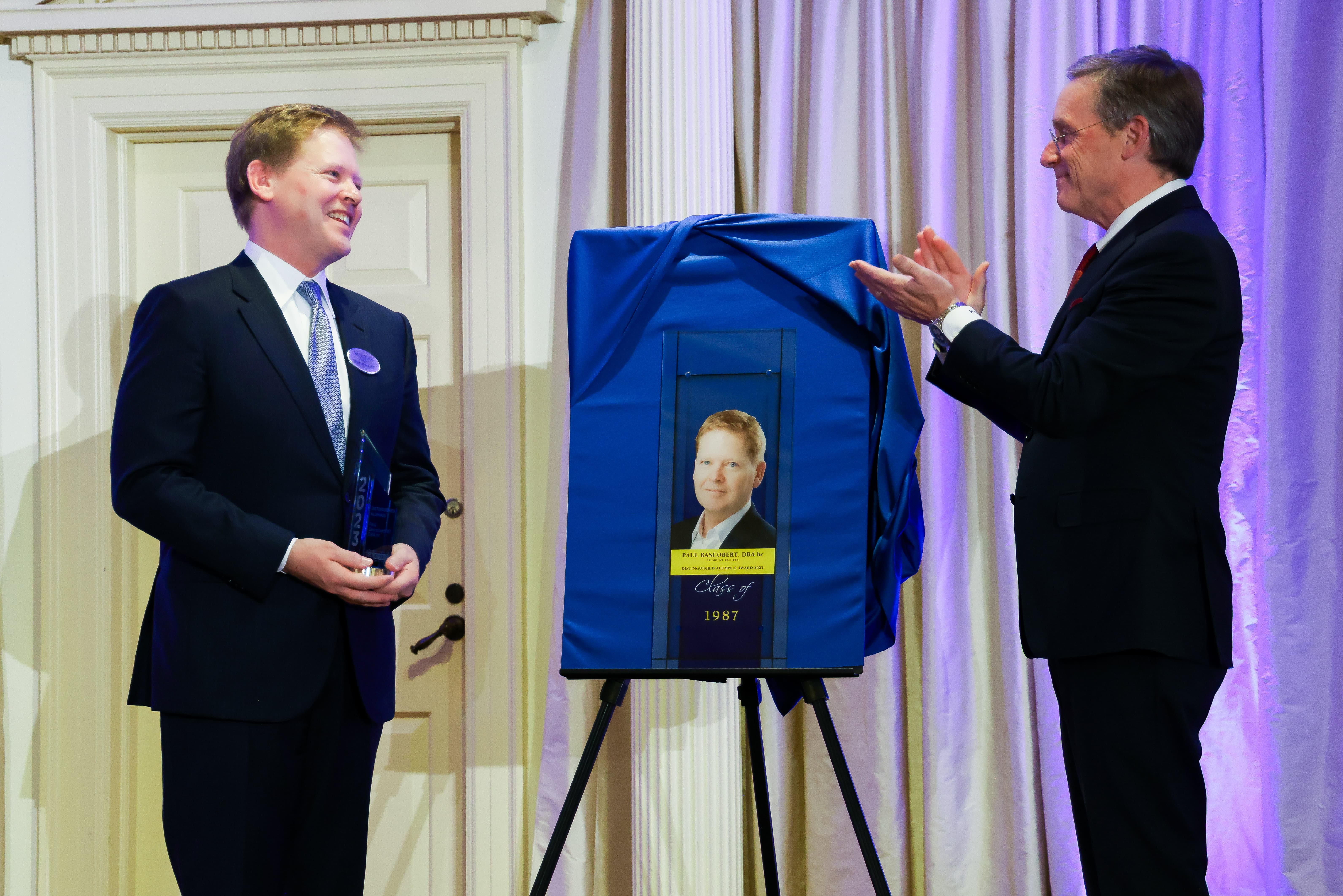 Kettering University President Dr. Robert K. McMahan unveils a plaque honoring Paul Bascobert.