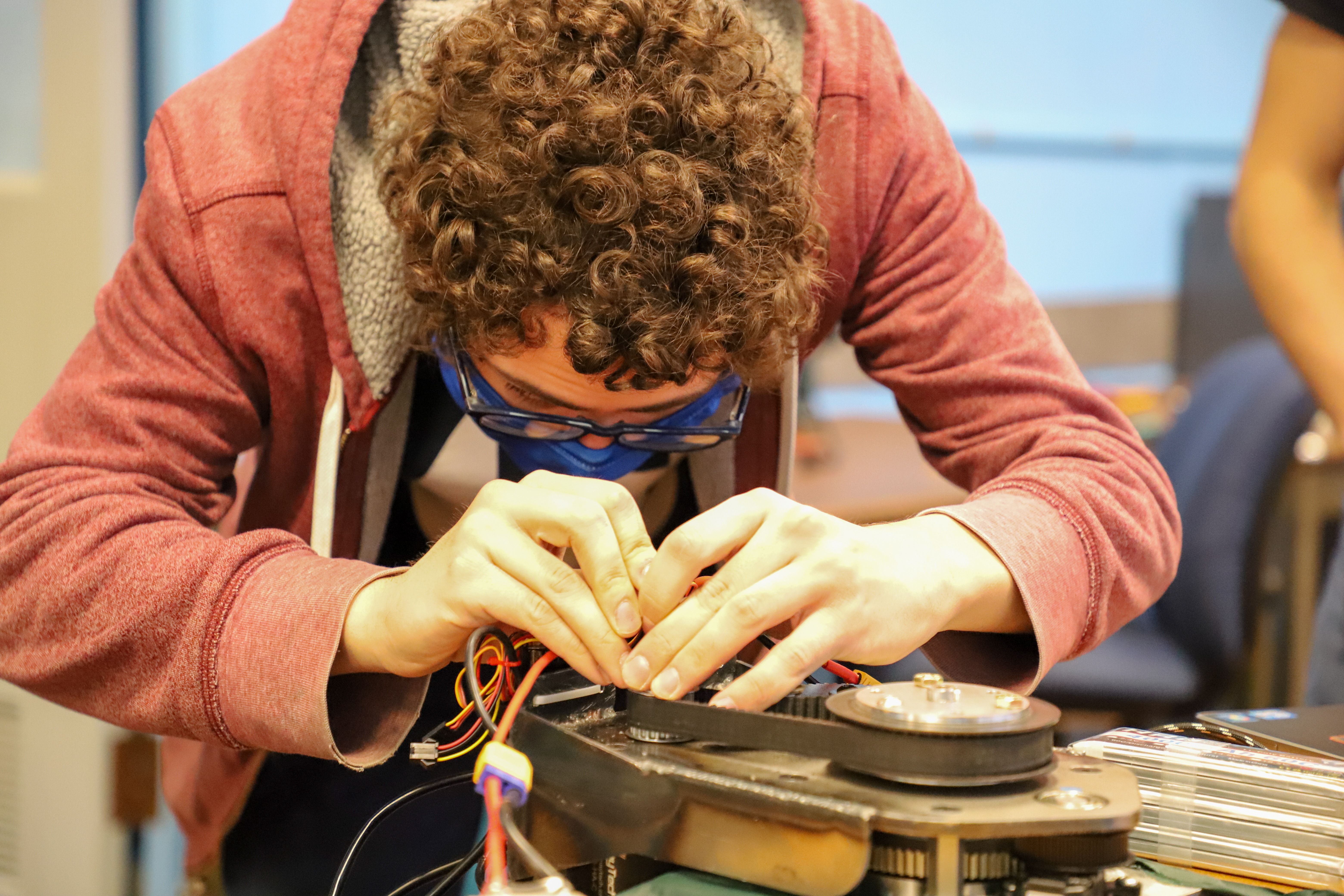 A Kettering University student works on the wiring of the robot's wheel.