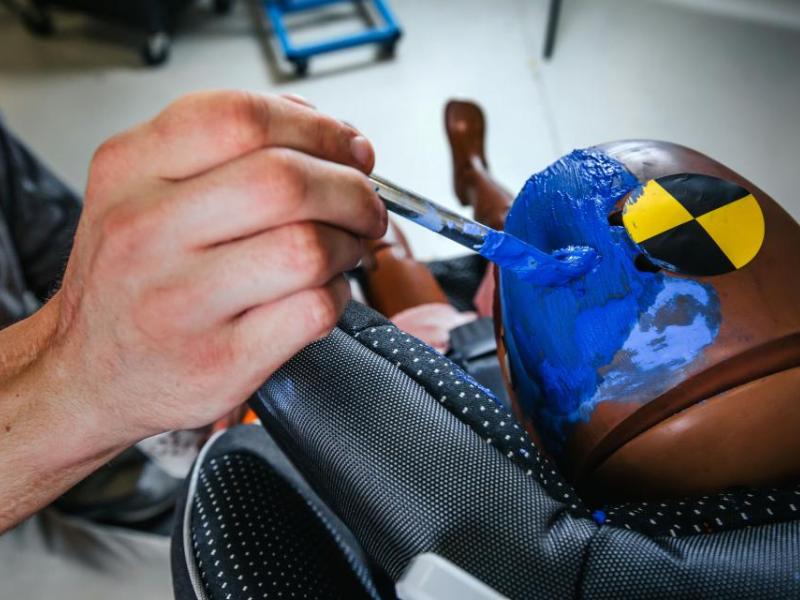 A crash test dummy is carefully prepared with paint markers at Kettering University's Crash Safety Center, ensuring precise impact analysis for automotive safety research.