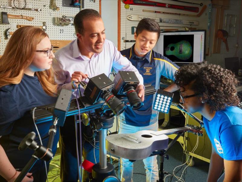 Students collaborate with a professor in Kettering University's Noise, Vibration, and Harshness and Experimental Mechanics Laboratory, using advanced imaging technology to study acoustic properties of a guitar.