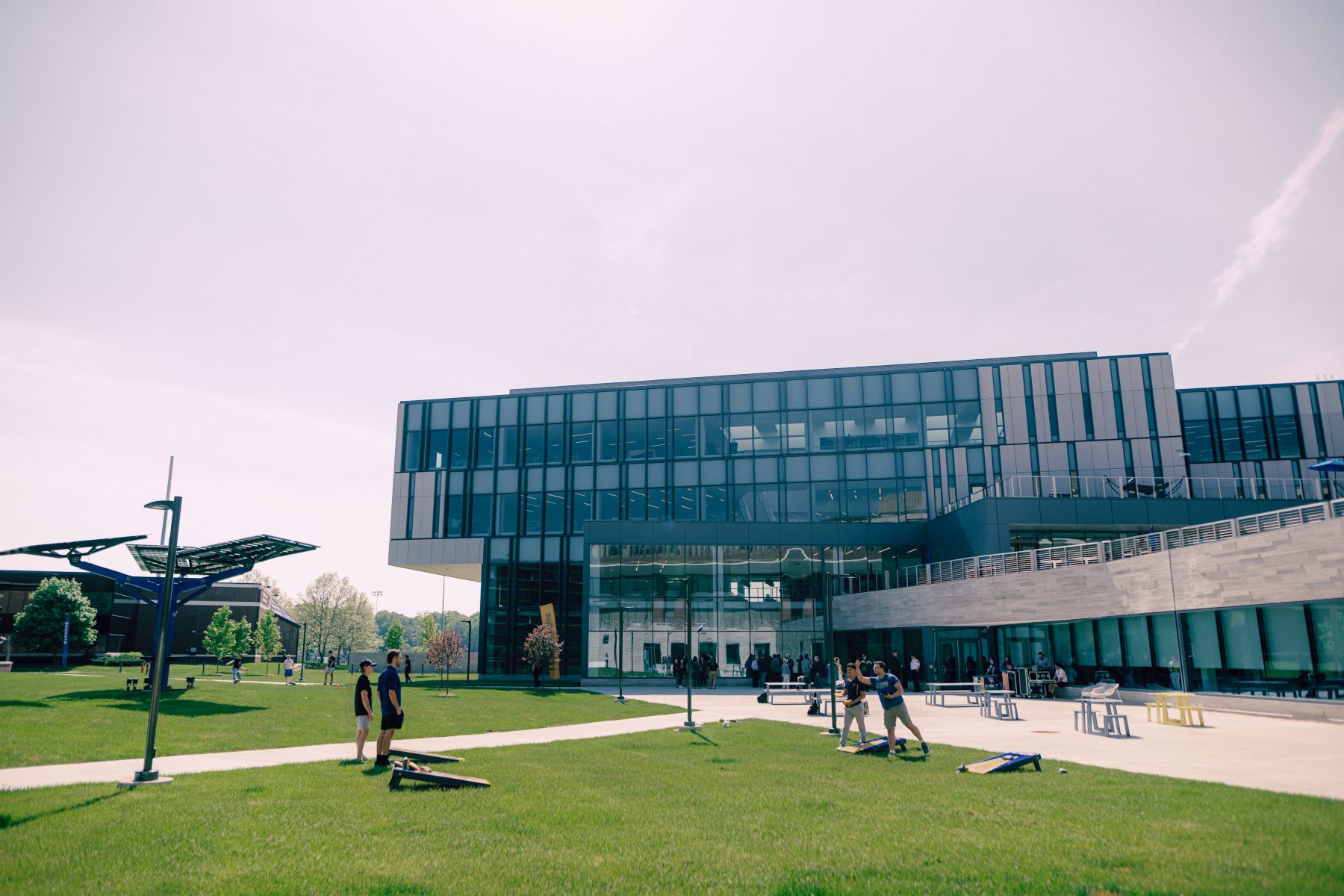 Four Kettering students play cornhole on the lawns in front of the Learning Commons