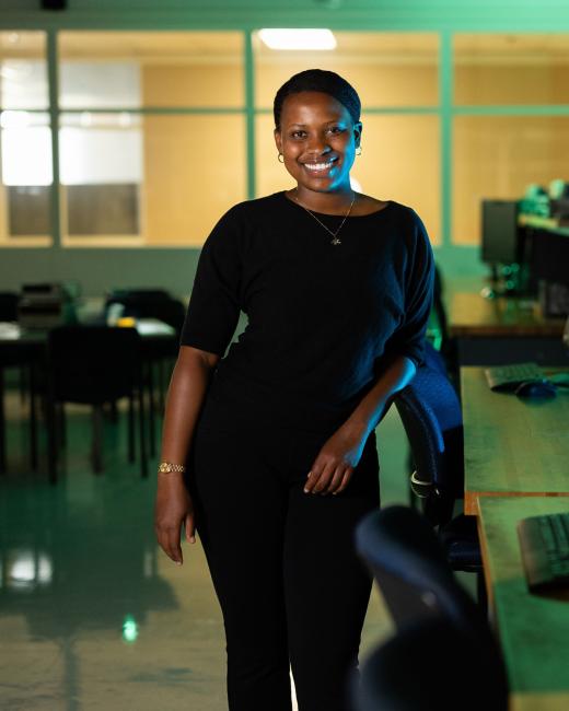 Kettering computer engineering student Tanisha Frances stands in an empty classroom next to desks with computers