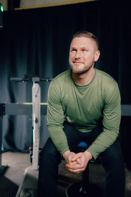 Kettering electrical engineering alum Peter Deppe sits in a stool next to an electric scooter