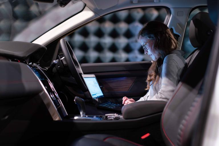 A woman inside a car with a laptop working