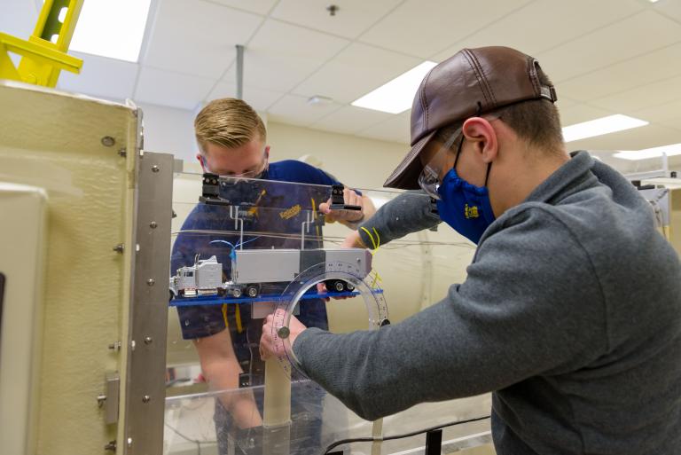 Two Kettering University students work on a machine.
