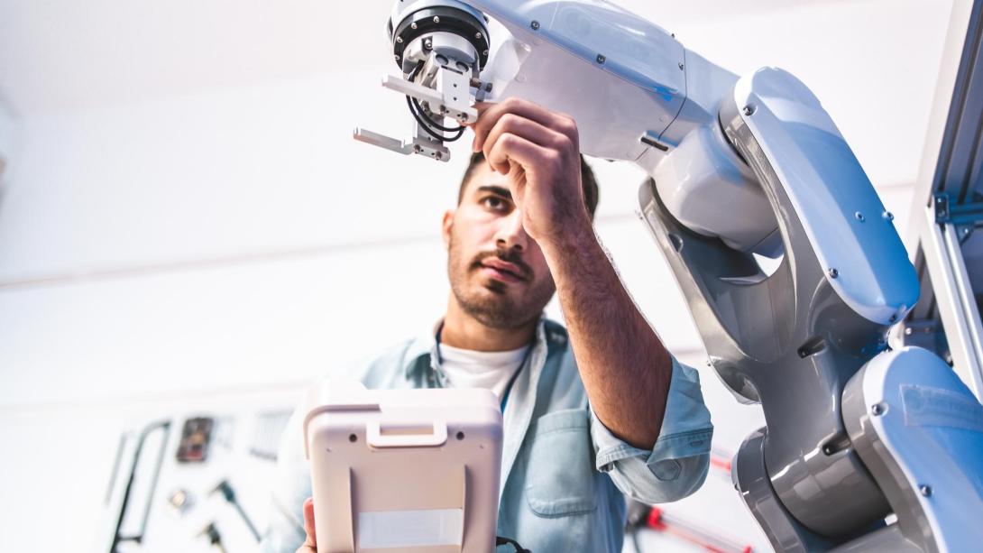 Co-op student working on an automated manufacturing robot arm