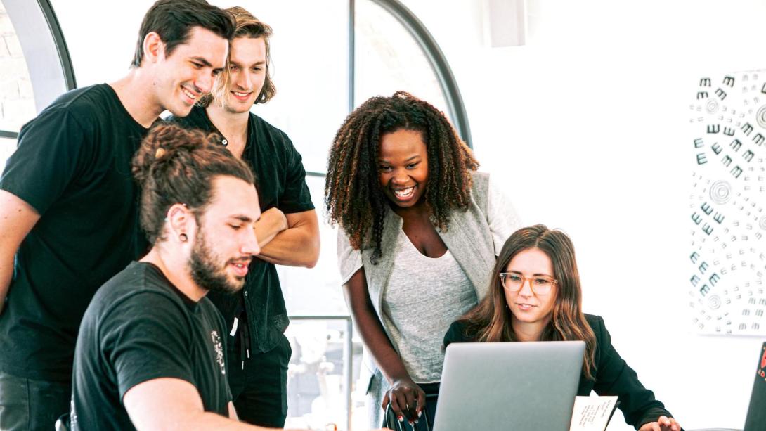 A group of people collaborating around a laptop