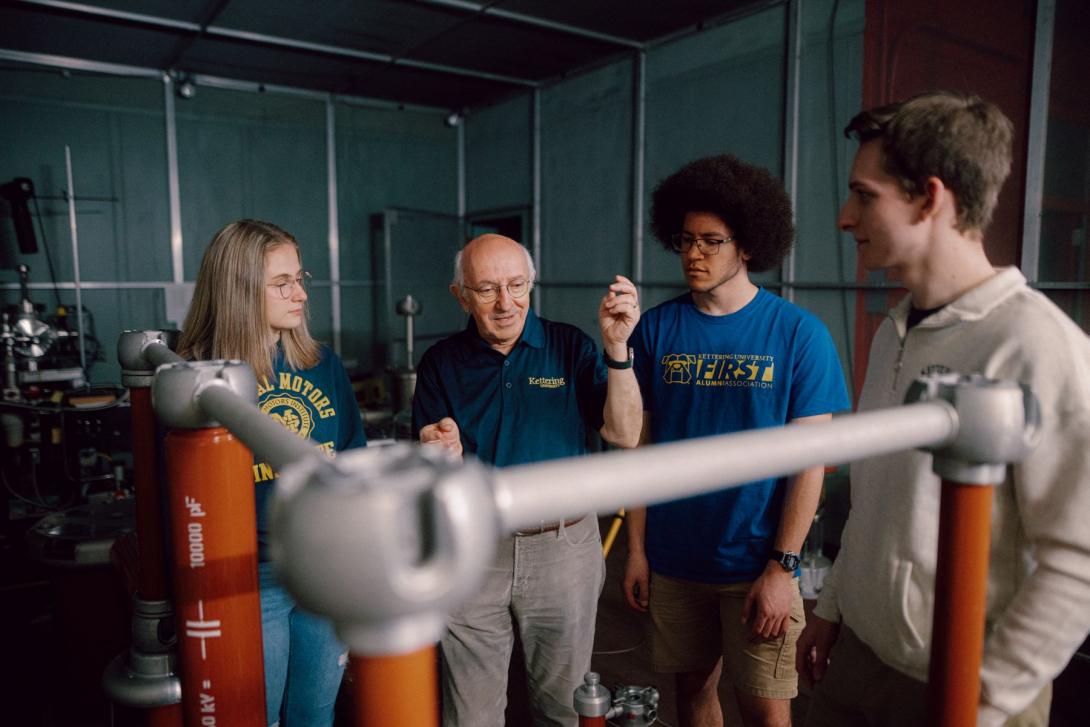 A Kettering professor explains electrical engineering concepts to three students in the High Voltage Lab