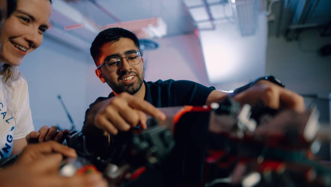 Three Kettering mechanical engineering students inspect car parts in the Car Lab.