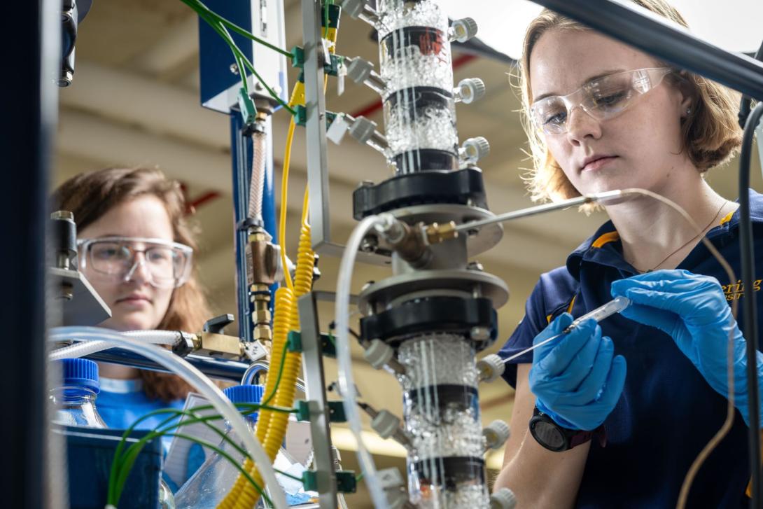 Two Kettering chemical engineering students insert liquid into lab equipment in the Chemical Engineering Teaching Lab