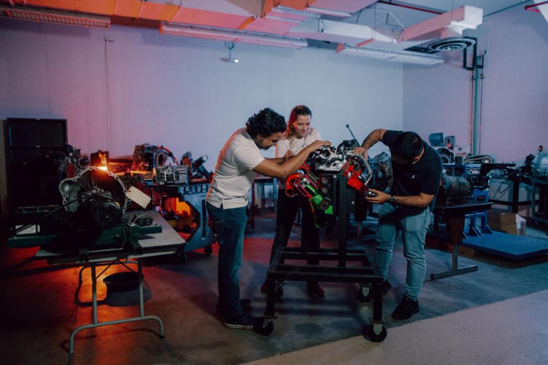 Three Kettering mechanical engineering students in the Car Lab take a close look at a car part