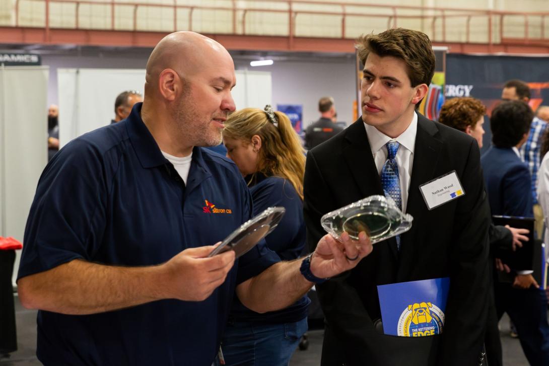 A recruiter at Kettering's Co-Op Fair talks to a Kettering student and shows off his company's products