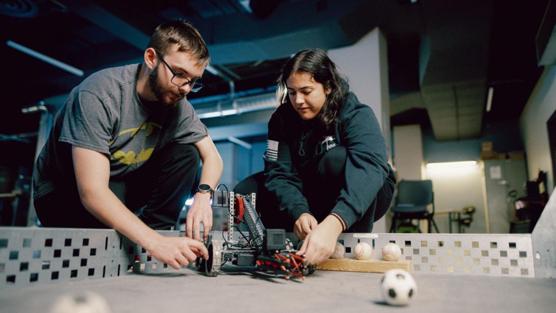 Two Kettering engineering students prepare to test a robot in a course filled with miniature balls