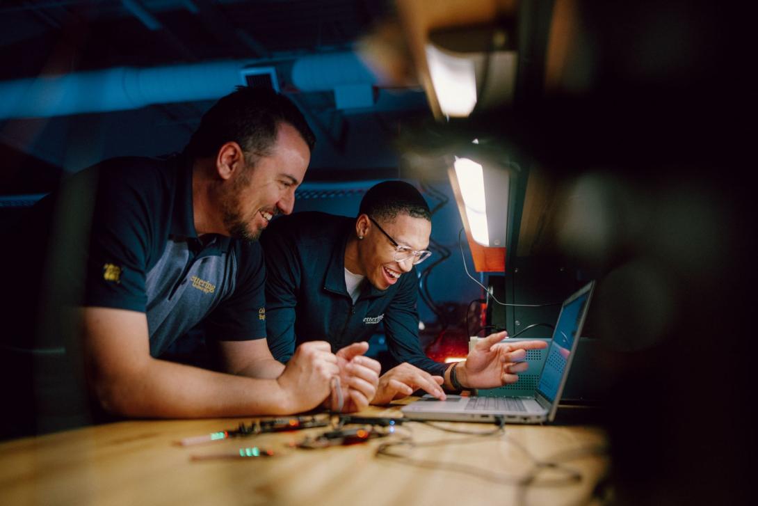 Two Kettering engineering students view the results of an experiment on a laptop screen. They're both smiling