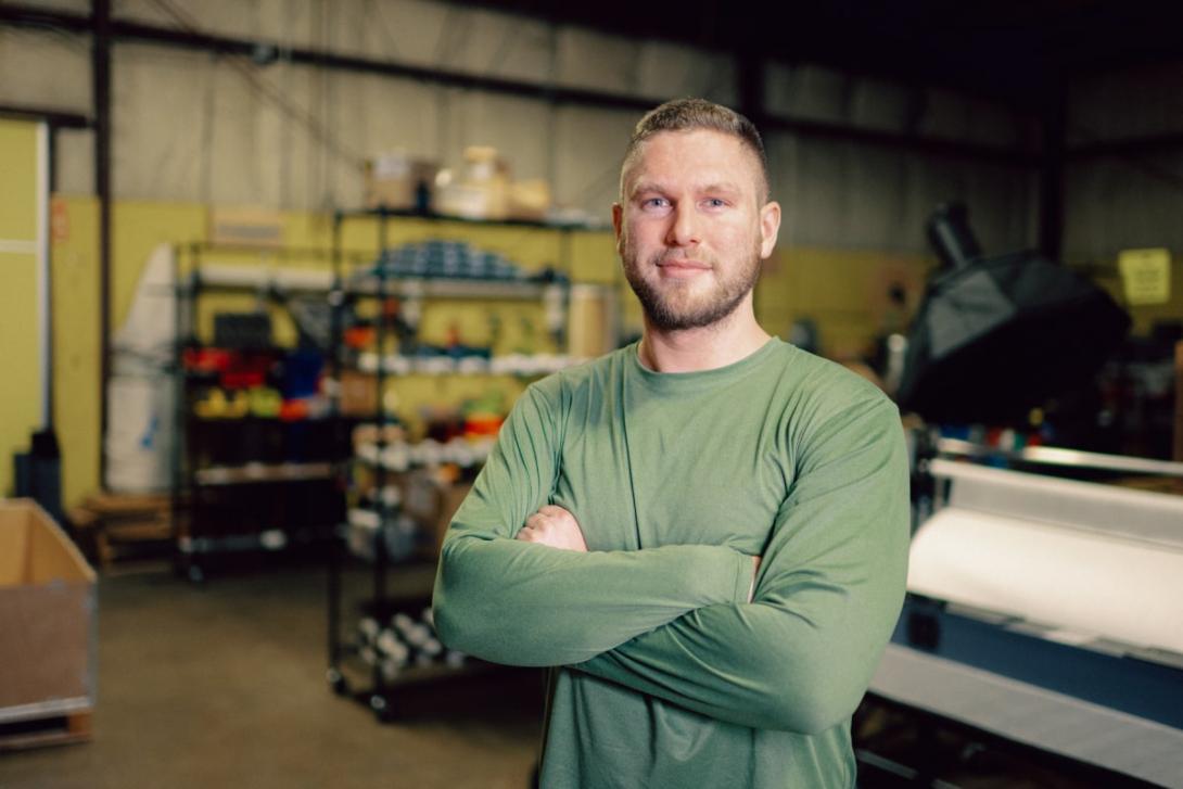 Kettering alum Peter Deppe stands with arms crossed inside a Kettering garage