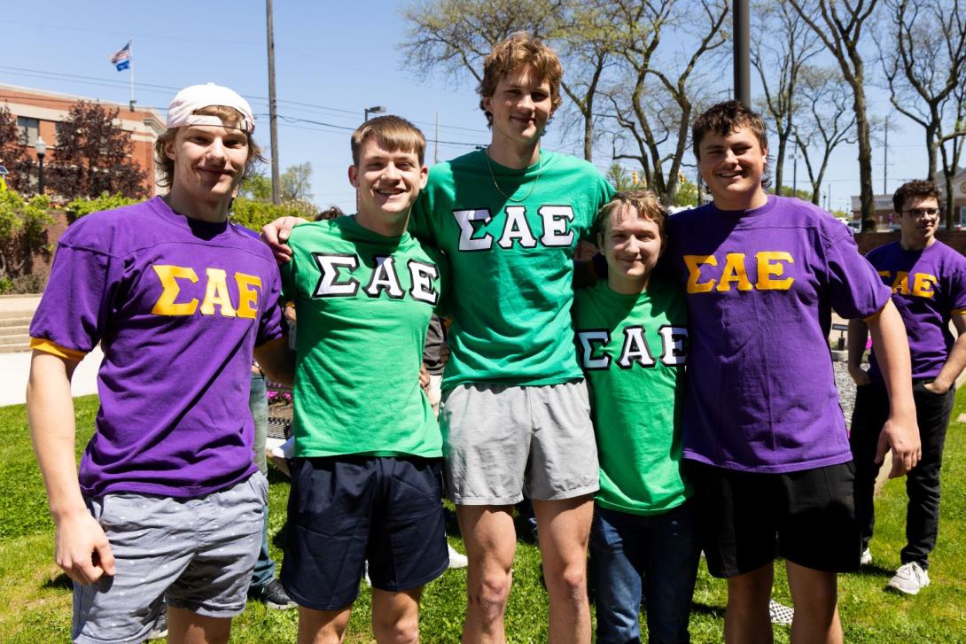 Five Kettering students wear purple or green Sigma Alpha Epsilon fraternity shirts