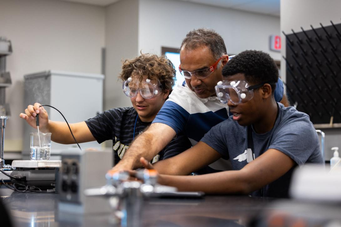 One Kettering professor and two students wear safety glasses while they conduct an experiment.