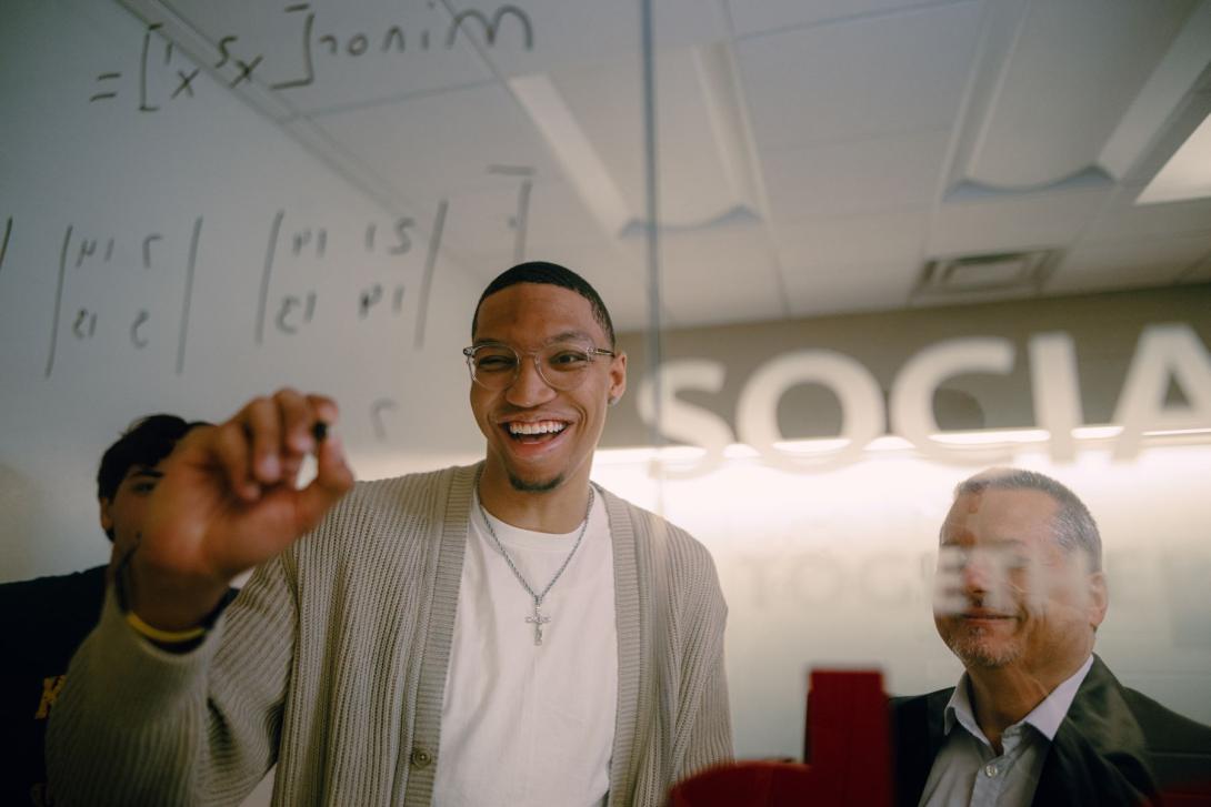 Kettering management student matrix equations on a glass wall. Another student and a professor watch