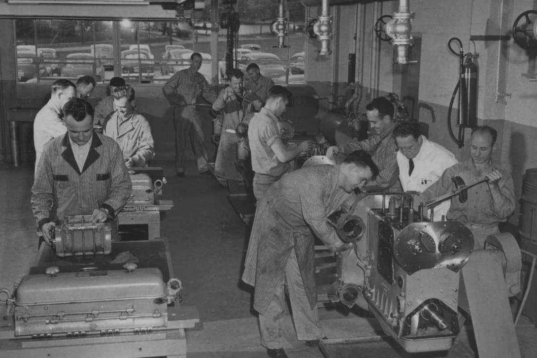 A black-and-white photo from the 1950s-1970s of Kettering students working on car parts in an automotive garage