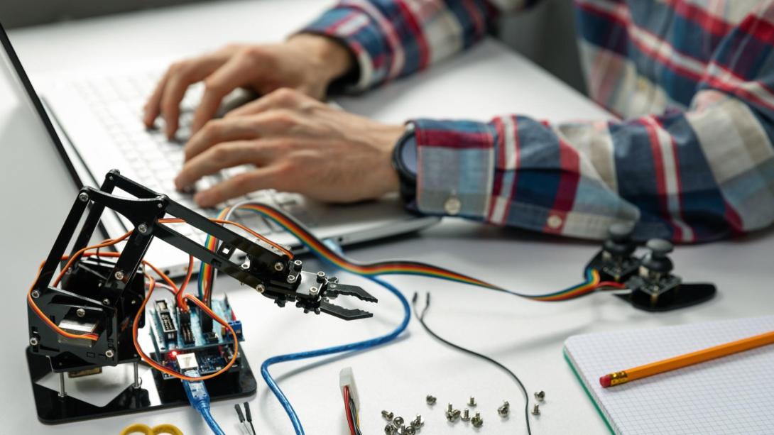 Student hands programming the wiring for a robotic arm