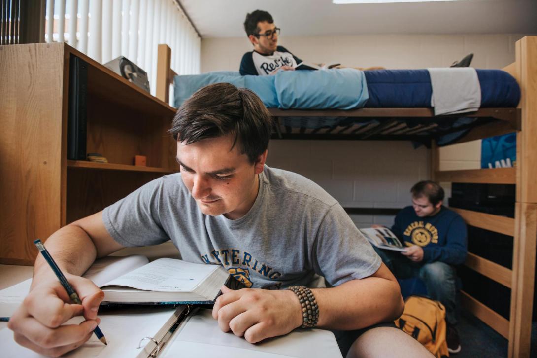 Three students studying together in a dorm room