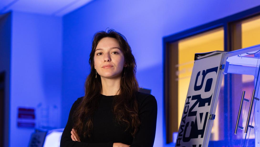 A student stands with arms crossed in a lab