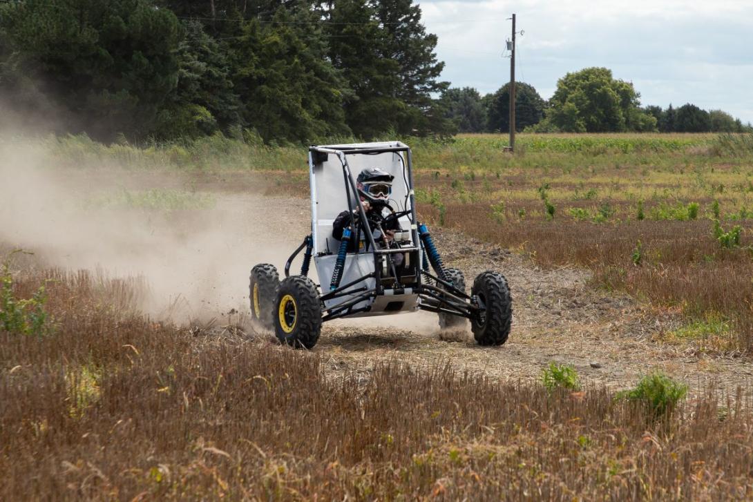 A Kettering student is driving an off-road vehicle, testing it in preparation for the Baja SAE competition