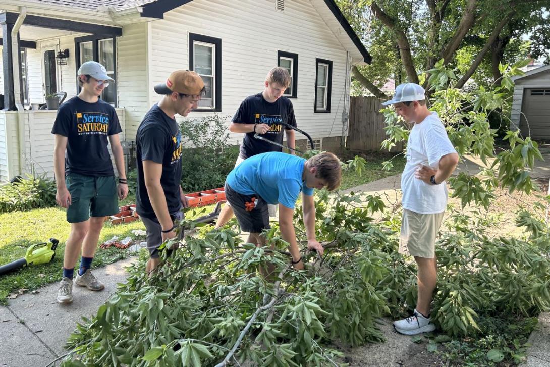 A group of five Kettering students cut and clear tree branches in a neighborhood for Service Saturday