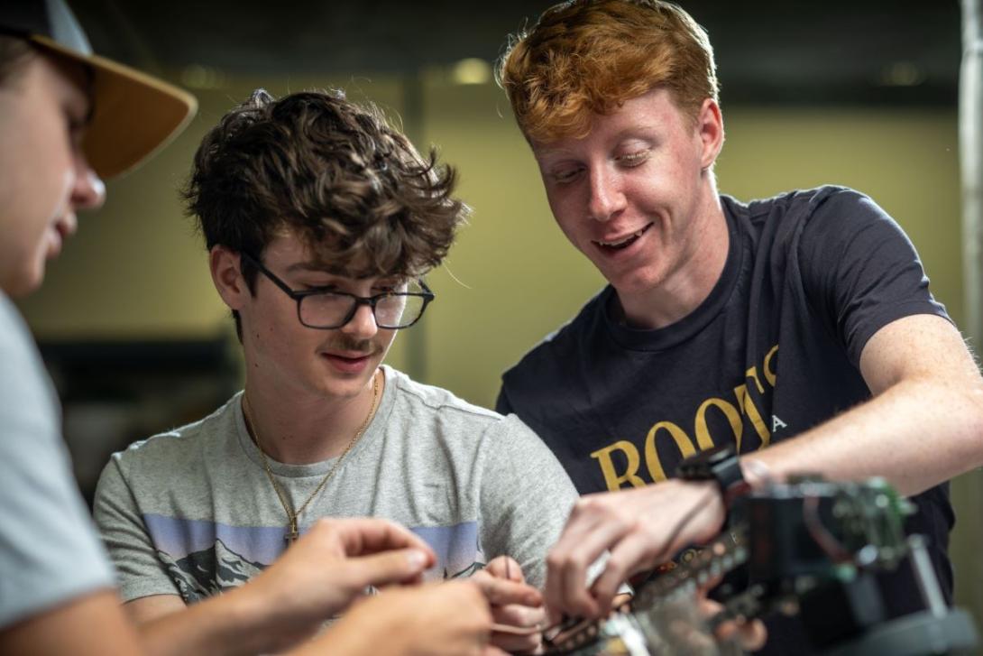 Three students using equipment