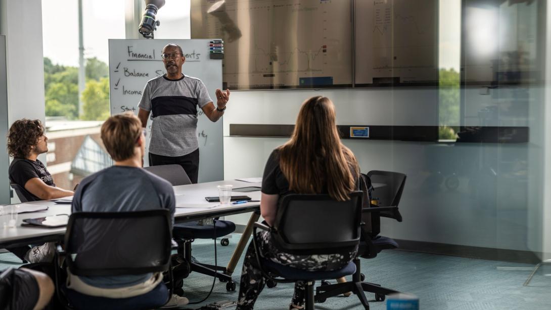 A professor teaches a group of students sitting at a table in the Learning Commons