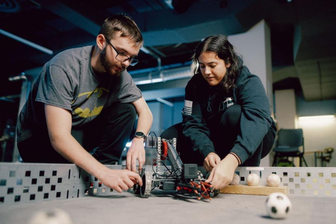 Two Kettering engineering students prepare to test a robot in a course filled with miniature balls