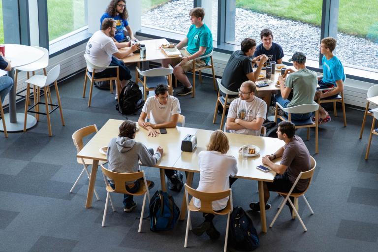 Groups of students gather for meals and discussions in the open and inviting seating area of the Learning Commons.