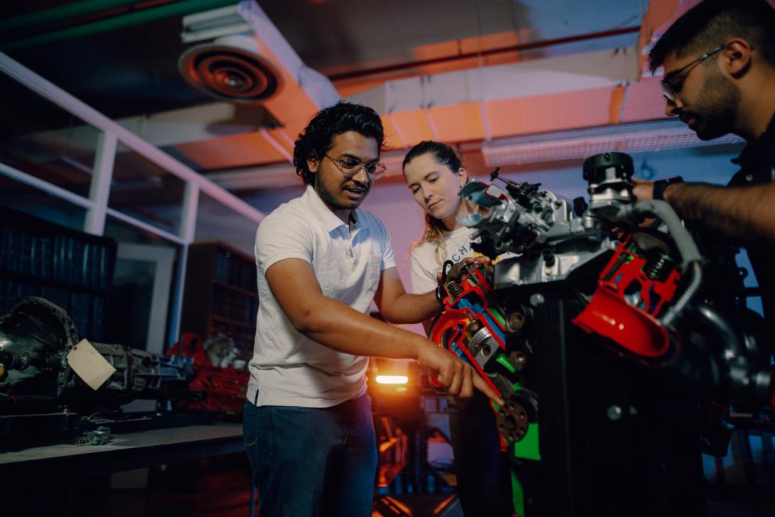 students working on car engine in lab